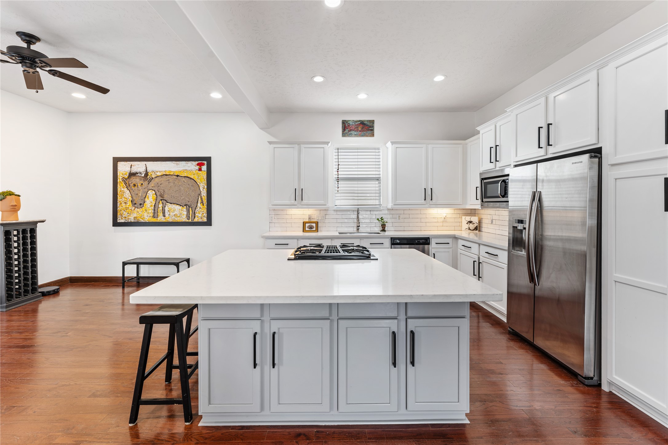 415 West 8th Street Houston, TX 77007 - Photo 27 of 39 At the heart of the home, this stunning chef's kitchen features an oversized quartz island with seating, custom shaker-style cabinetry, stainless steel appliances, and a gas cooktop perfectly positioned for gathering with family and friends. Generous prep space and abundant storage make this kitchen as functional as it is beautiful.