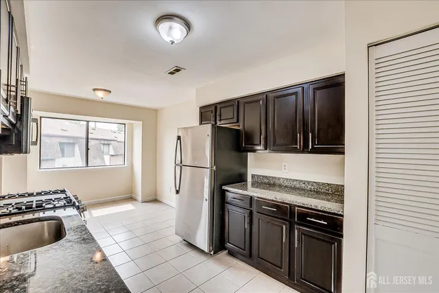 a kitchen that has a sink a refrigerator and cabinets