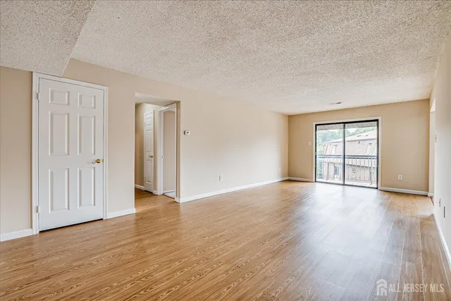 a view of an empty room with window and wooden floor