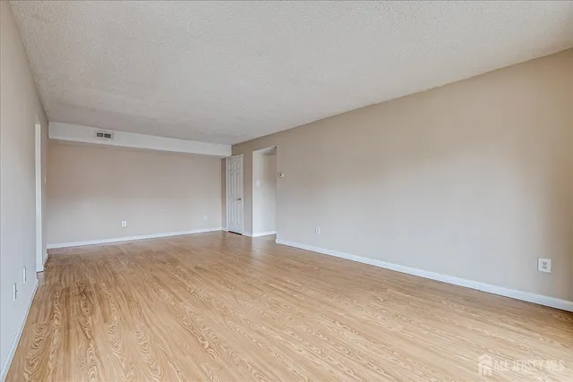 a view of a refrigerator in kitchen and an empty room