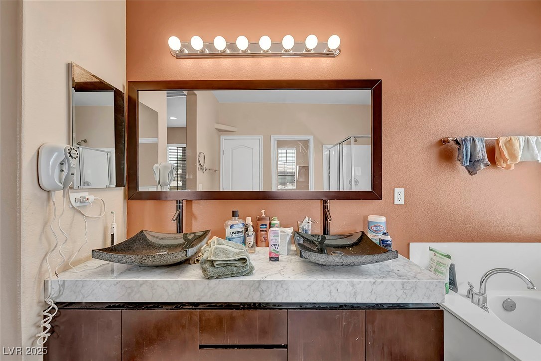 8208 Seven Falls Street North Las Vegas, NV 89085 - Photo 27 of 69 Full bathroom featuring a textured wall, double vanity, a garden tub, and an enclosed shower