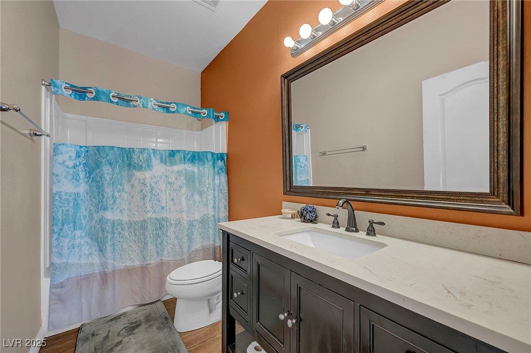 8208 Seven Falls Street North Las Vegas, NV 89085 - Photo 40 of 69 Bathroom featuring vanity, shower / bathtub combination with curtain, and wood finished floors
