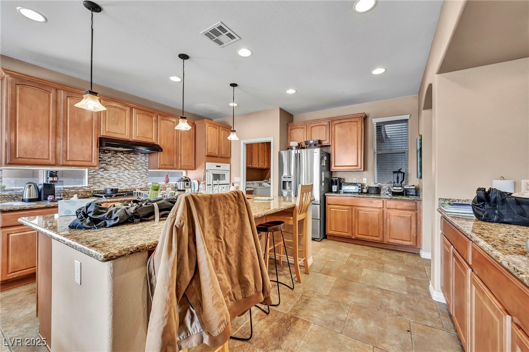 8208 Seven Falls Street North Las Vegas, NV 89085 - Photo 6 of 69 Kitchen with tasteful backsplash, stainless steel refrigerator with ice dispenser, recessed lighting, a kitchen bar, and a kitchen island with sink