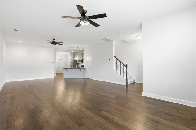 a view of an empty room with wooden floor and a ceiling fan