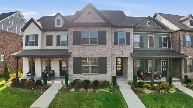 a view of a brick house with a big yard and large trees