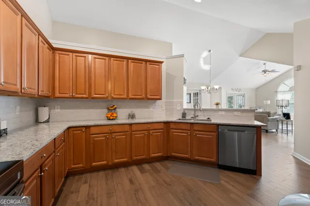 a kitchen with stainless steel appliances granite countertop wooden cabinets a sink and dishwasher with wooden floor
