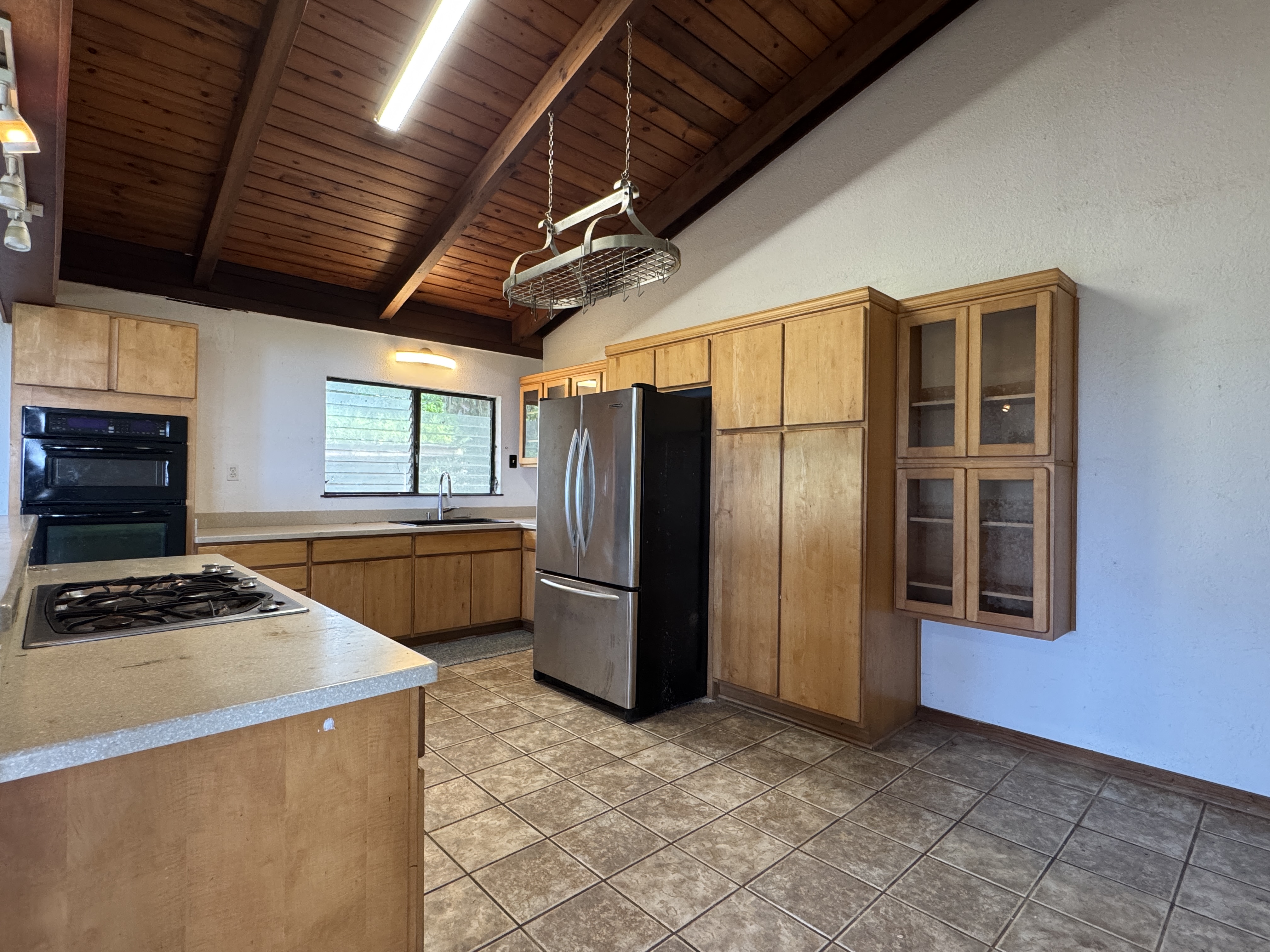 84-5040 Hawaiʻi Belt Road Captain Cook, HI 96704 - Photo 11 of 30 a kitchen that has a refrigerator a stove and a sink with wooden floor