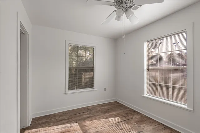 a view of an empty room with a window and wooden floor