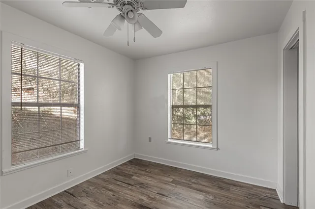 a view of an empty room with a window and wooden floor