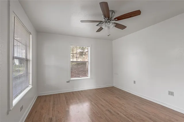 a view of empty room with wooden floor and fan