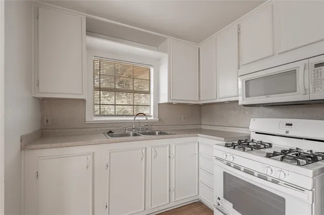 a kitchen with granite countertop white cabinets and white appliances