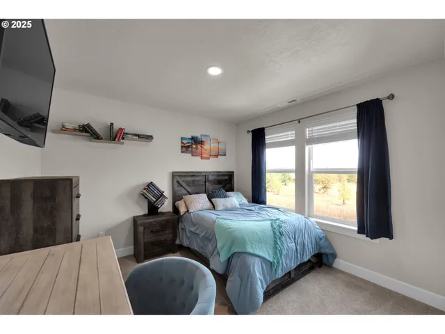 a bedroom with a bed and a flat tv screen on the dresser