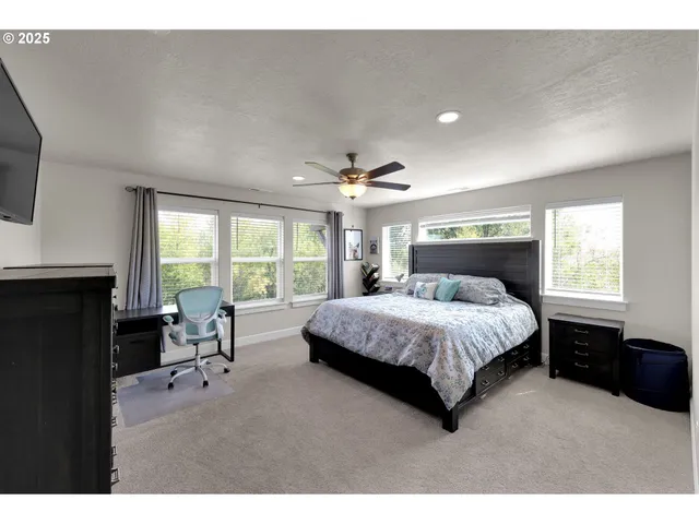 a spacious bedroom with a bed a table and large window