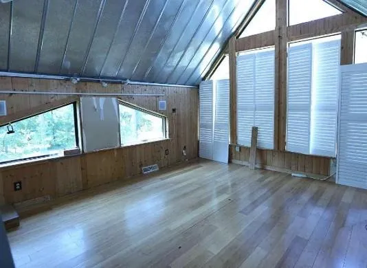 a view of an empty room with wooden floor and a window
