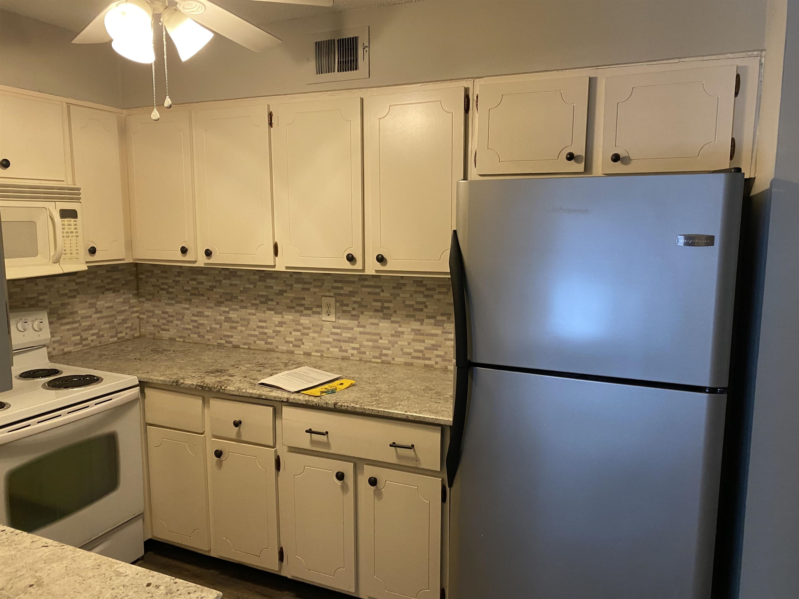 5696 Quince Road, Unit 7 Memphis, TN 38119 - Photo 11 of 15 a kitchen with stainless steel appliances granite countertop white cabinets and a refrigerator a stove top oven