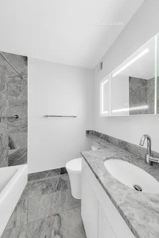 a bathroom with a granite countertop sink a toilet and bathtub