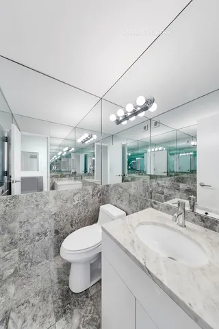 a bathroom with a granite countertop sink a toilet a mirror and vanity