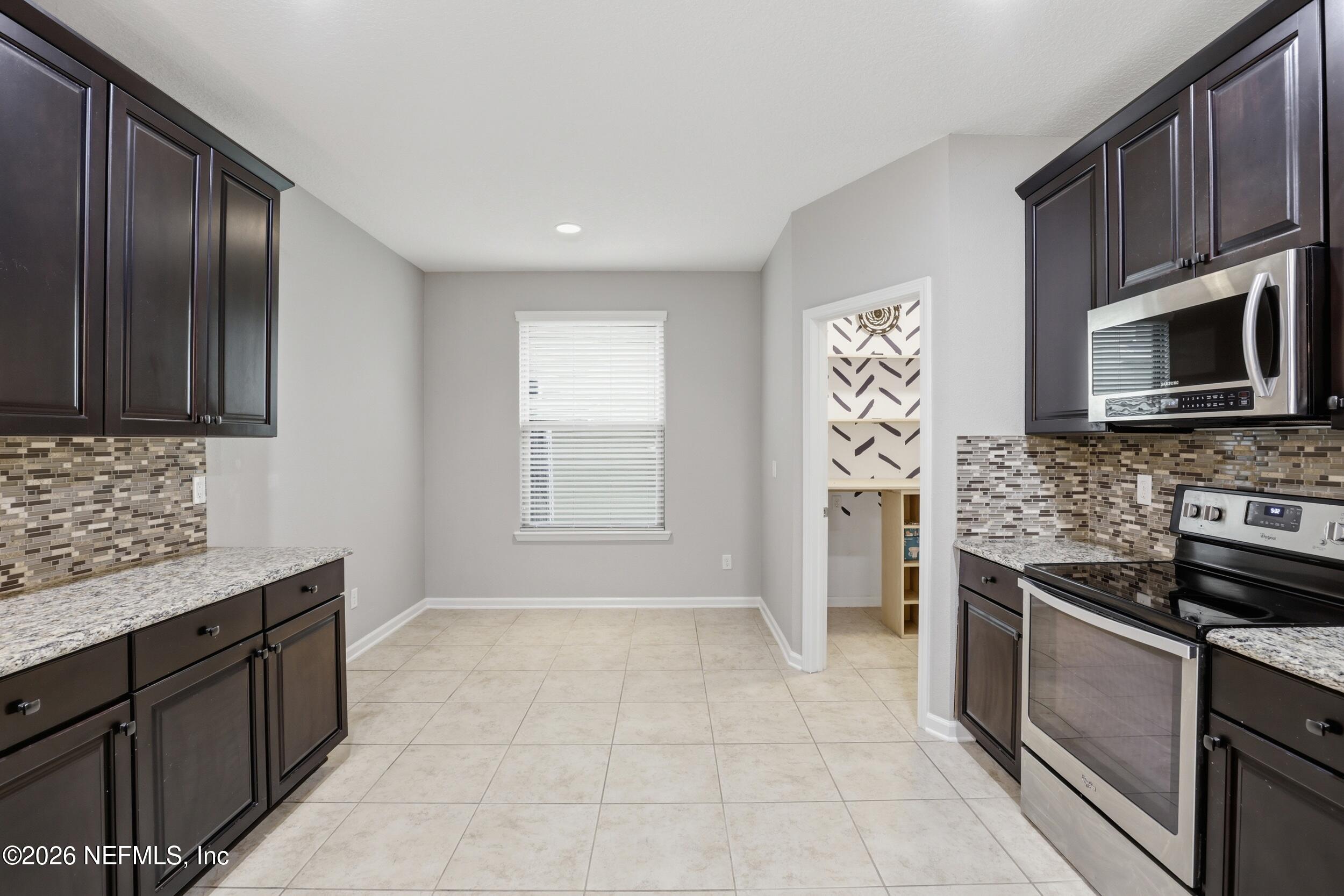 219 Straw Pond Way St. Augustine, FL 32092 - Photo 16 of 36 a kitchen with stainless steel appliances granite countertop a stove microwave and sink