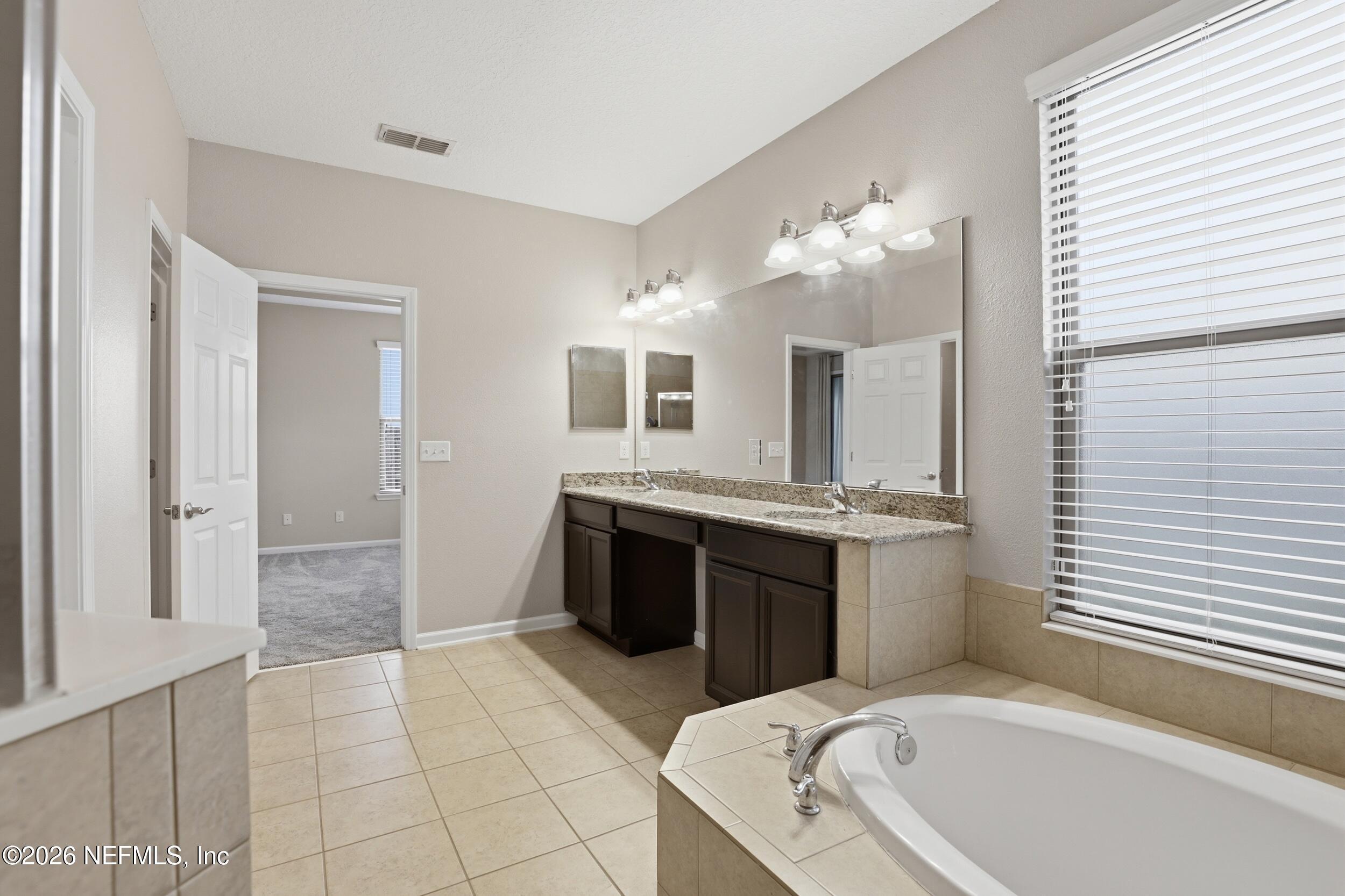219 Straw Pond Way St. Augustine, FL 32092 - Photo 22 of 36 a spacious bathroom with a granite countertop tub sink and a mirror