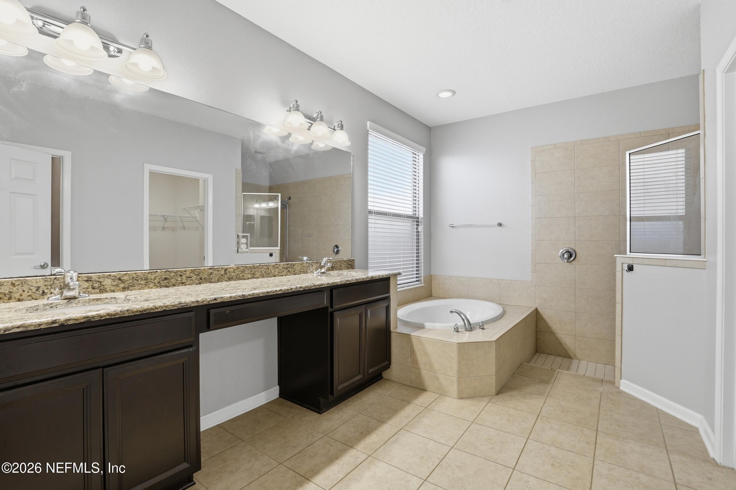 219 Straw Pond Way St. Augustine, FL 32092 - Photo 23 of 36 a spacious bathroom with a granite countertop sink toilet a mirror and a shower