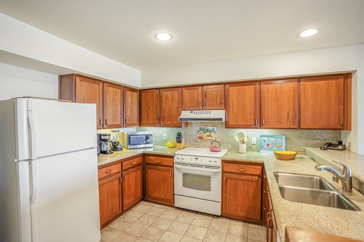 2221 Kapili Road, Unit 58 Koloa, HI 96756 - Photo 8 of 30 a kitchen with a refrigerator sink and white cabinets