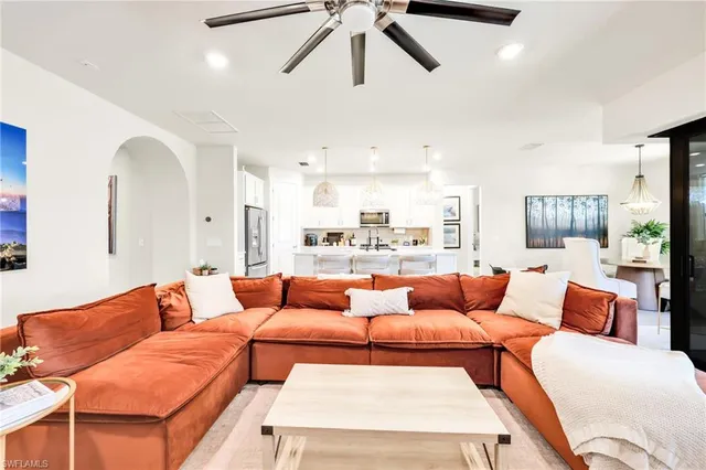 a living room with furniture a ceiling fan and a large window