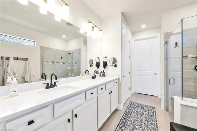 a bathroom with double vanity sinks a mirror a vanity and shower