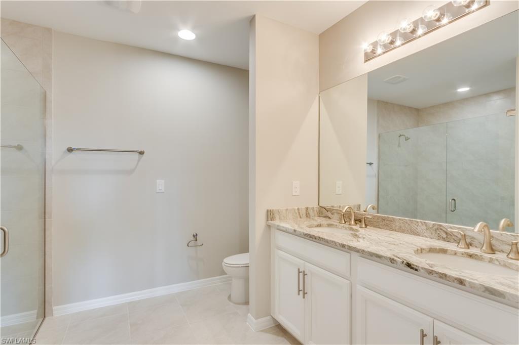 14863 Edgewater Circle Naples, FL 34114 - Photo 15 of 35 a bathroom with a granite countertop sink a toilet and a mirror