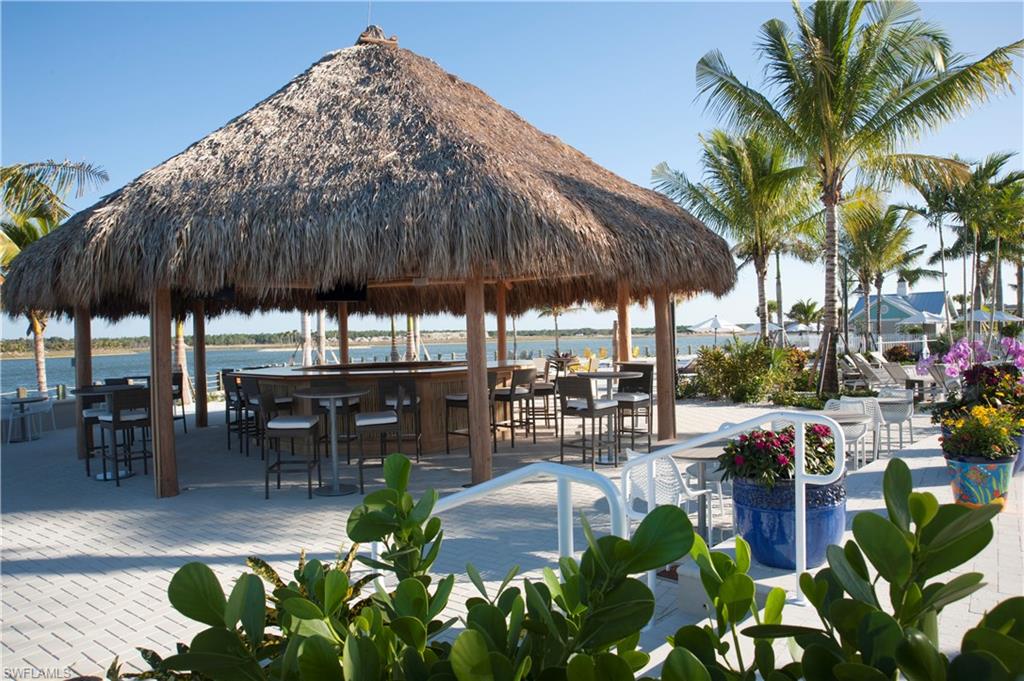 14863 Edgewater Circle Naples, FL 34114 - Photo 24 of 35 a patio with a table and chairs under an umbrella