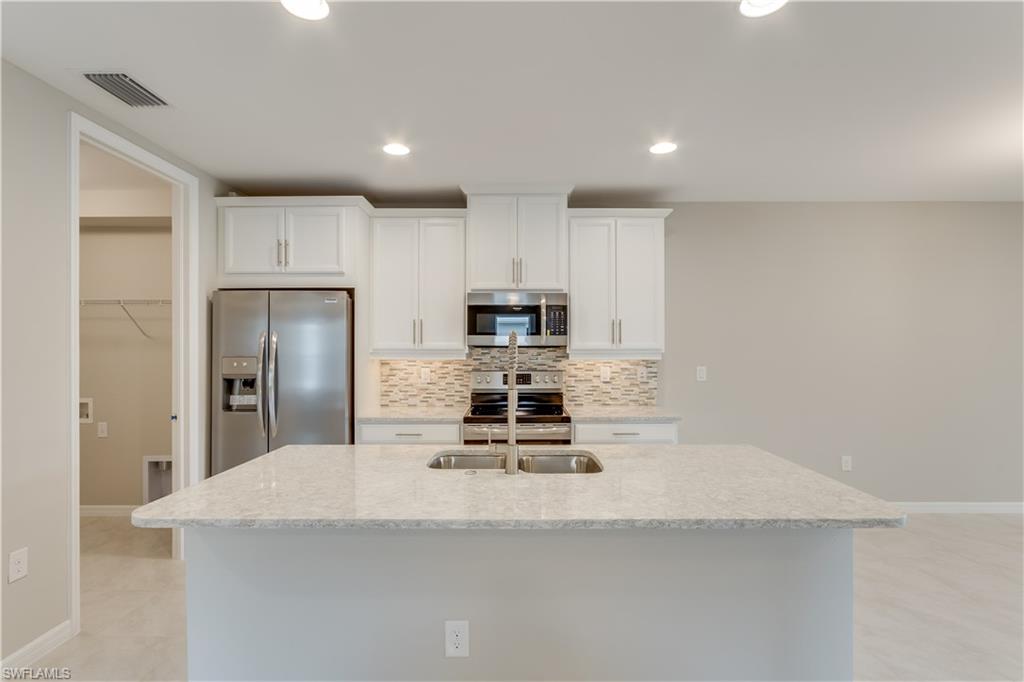 14863 Edgewater Circle Naples, FL 34114 - Photo 5 of 35 a kitchen with kitchen island a counter top space cabinets stainless steel appliances and cabinets