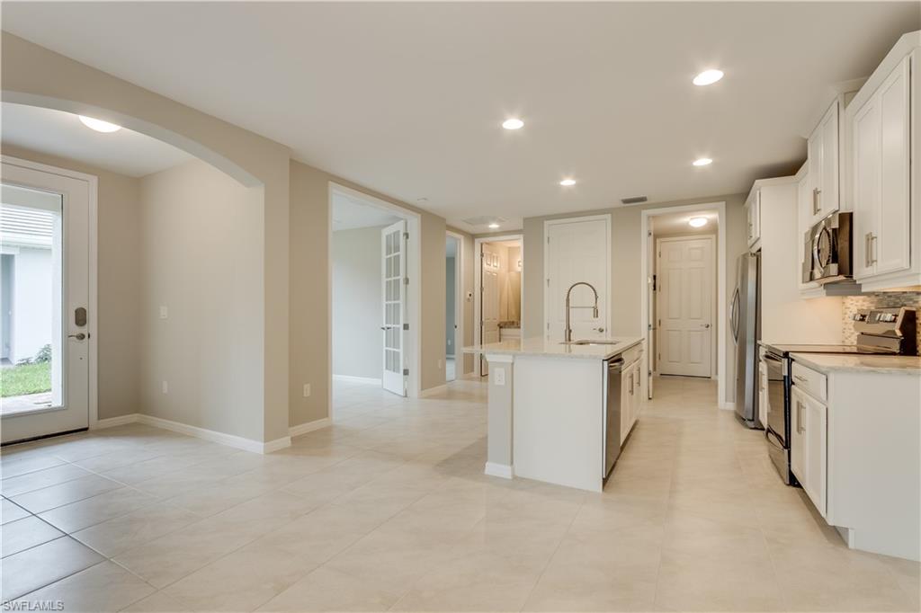 14863 Edgewater Circle Naples, FL 34114 - Photo 6 of 35 a large white kitchen with a refrigerator a stove top oven and cabinets