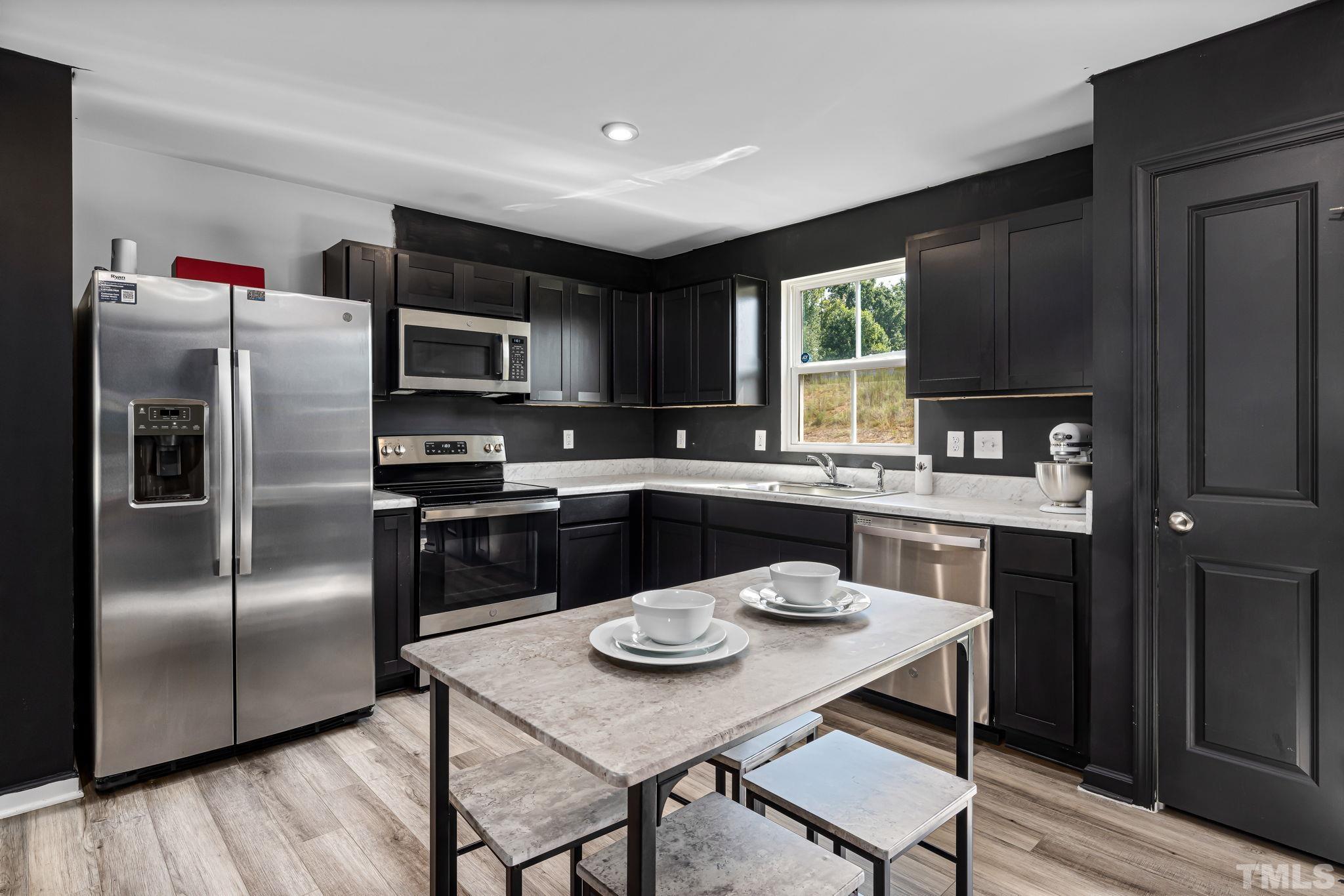 32 Powder Court Angier, NC 27501 - Photo 4 of 14 a kitchen with a refrigerator a stove a sink and a dining table with wooden floor