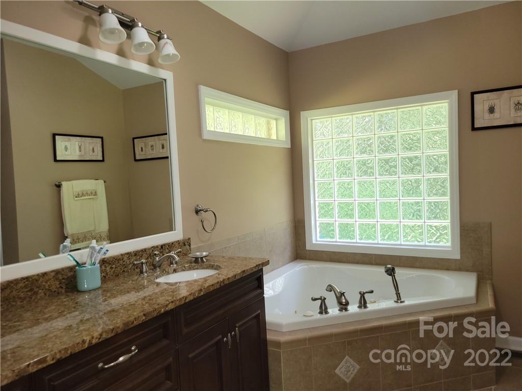 536 Biscoe Road Troy, NC 27371 - Photo 13 of 18 a bathroom with a granite countertop sink a mirror and a window