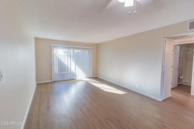 an empty room with wooden floor cabinet and windows