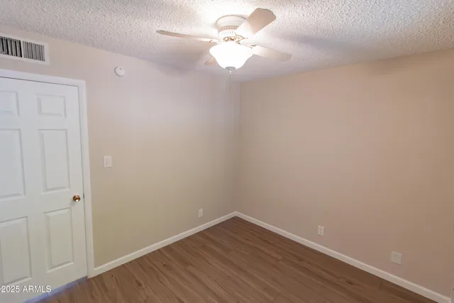 a view of a room with wooden floor and a ceiling fan