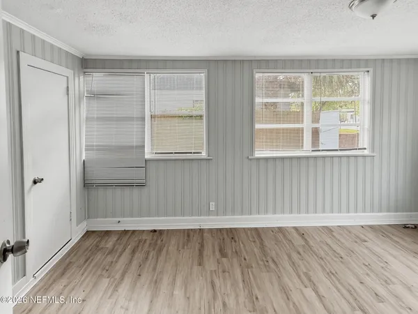 an empty room with wooden floor and windows