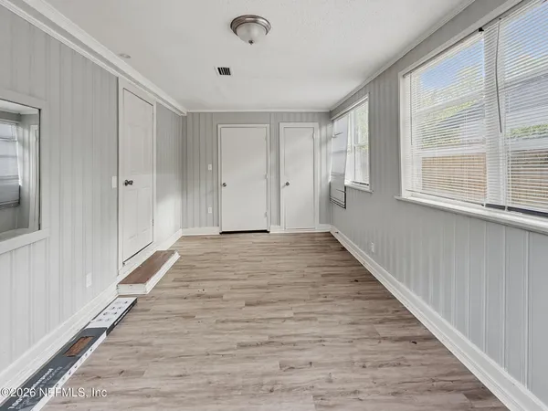 a view of an empty room with wooden floor and a window