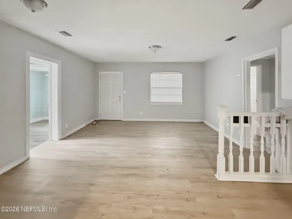 a view of an empty room with wooden floor and windows