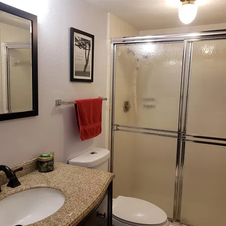 a bathroom with a granite countertop sink toilet and shower