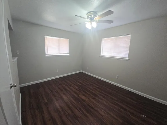 an empty room with wooden floor cabinet and windows