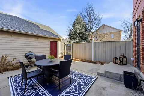 a backyard of a house with dining table and chairs