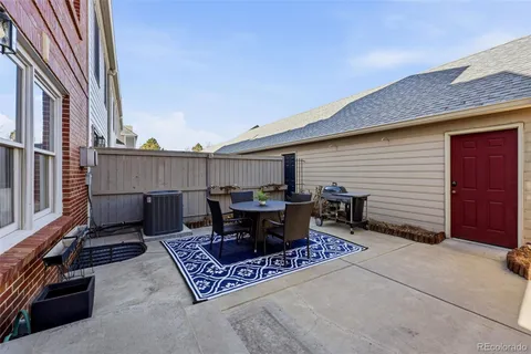 a view of a patio with table and chairs and wooden fence