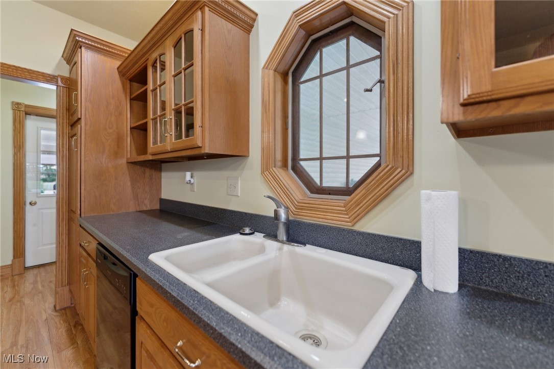 45230 Cemetery Road Wellington, OH 44090 - Photo 11 of 50 Kitchen with a sink, dishwasher, dark countertops, glass insert cabinets, and brown cabinetry
