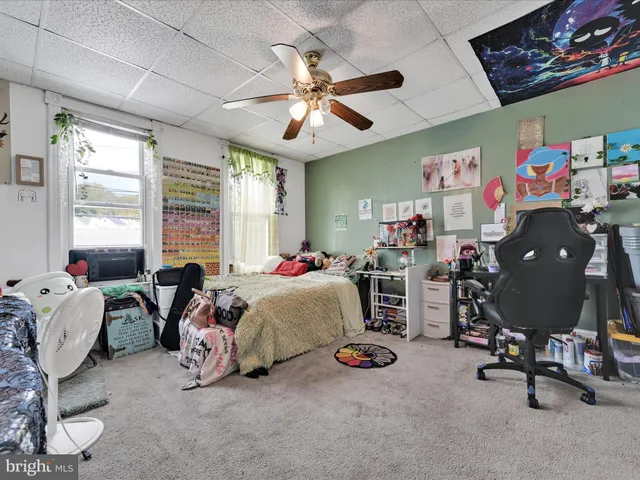 a bedroom with bed a ceiling fan and a large window
