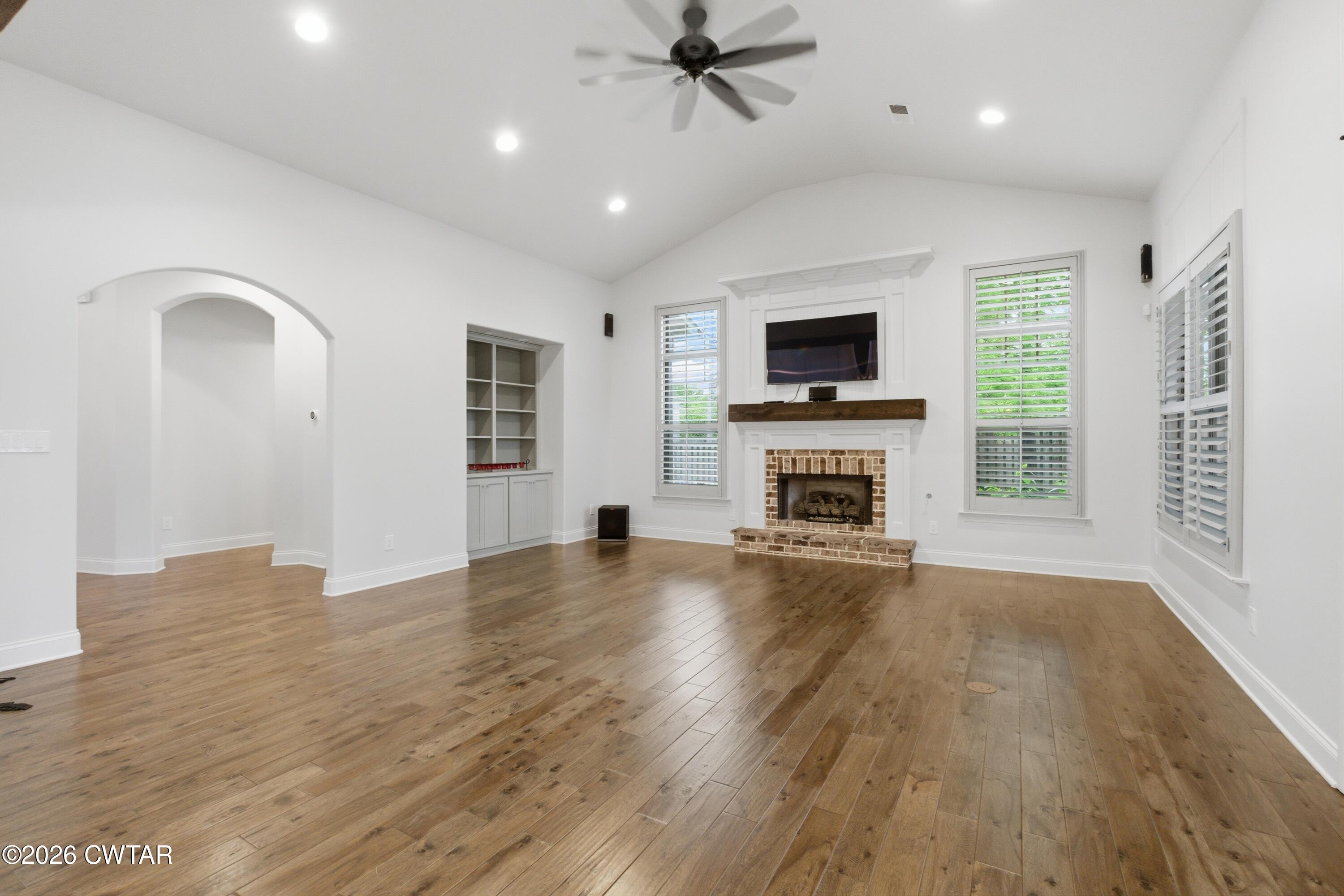 963 Ashport Road Jackson, TN 38305 - Photo 10 of 60 an empty room with windows fireplace and wooden floor