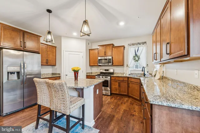 a kitchen with granite countertop kitchen island stainless steel appliances a stove sink and refrigerator