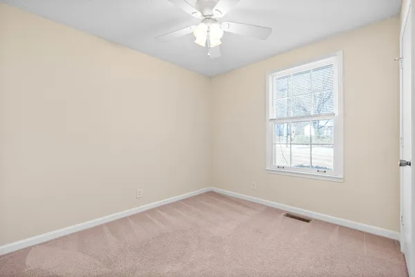 an empty room with a window and a fan