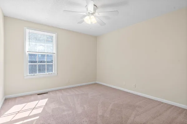 an empty room with a window and a fan
