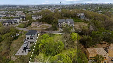 an aerial view of a residential houses with outdoor space and trees