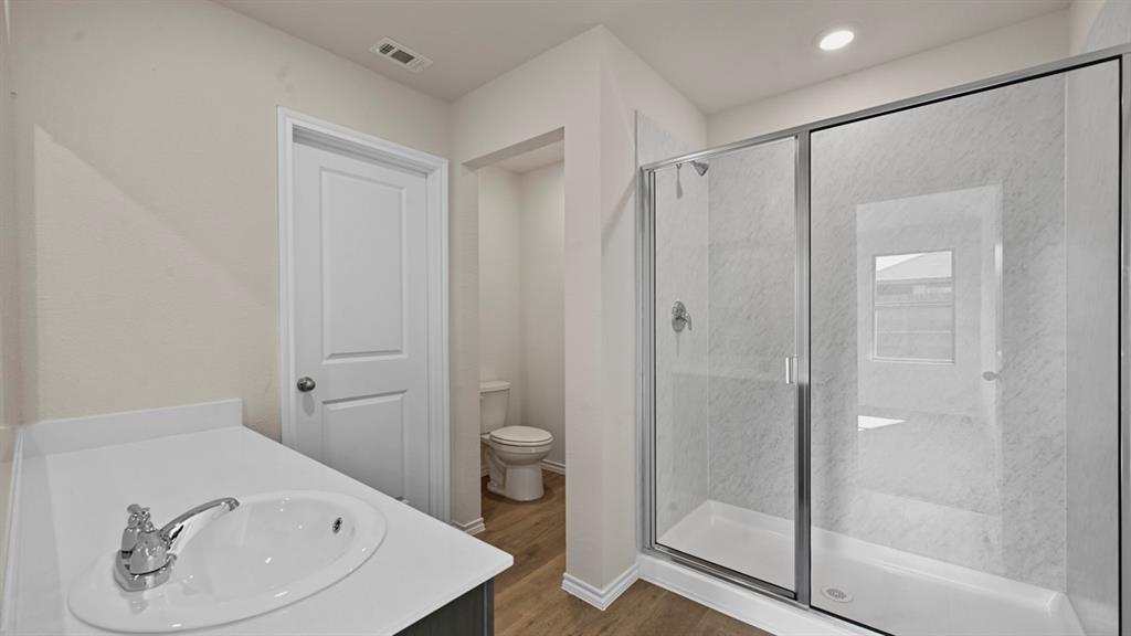 1663 Blaire Drive Tyler, TX 75704 - Photo 20 of 26 Bathroom featuring a clear glass shower enclosure with chrome fixtures, a single vanity with an undermount sink, and wood-finish flooring